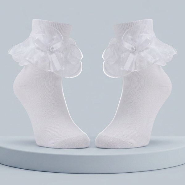 A pair of white ankle socks with layered ruffles and satin bows displayed on a pale pedestal.