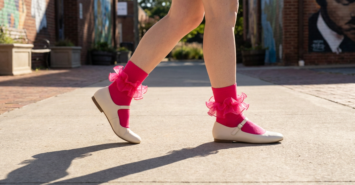 Hot pink ruffle ankle socks worn with cream Mary Jane flats, with the shoe straps and ruffle cuffs visible.