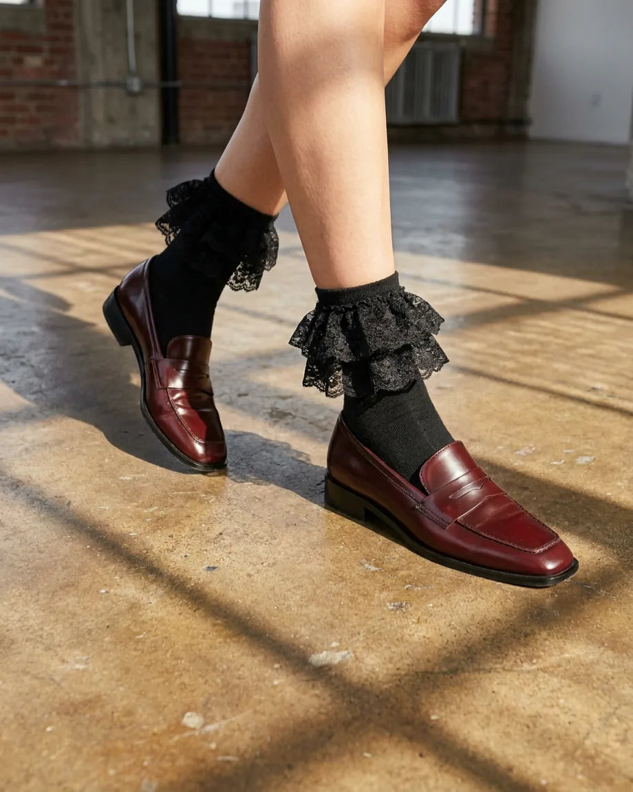 Woman styling black ruffle socks with oxblood loafers